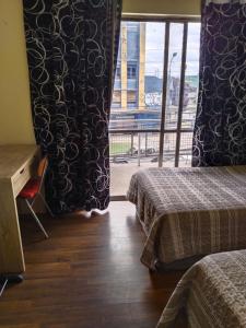 Cette chambre comprend deux lits et une fenêtre avec vue. dans l'établissement Hostal Donde Gabriel, à Chillán