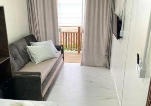 ein Wohnzimmer mit einem Sofa und einem TV in der Unterkunft Pousada São Miguel Beach Beira Mar in Penha