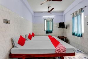 a bedroom with a bed with red pillows at OYO Flagship Sai Ganesh Deluxe Lodge in Tirupati