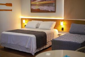 a hotel room with a large bed and a couch at O Azul de Maragogi - Pousada Premium in Maragogi