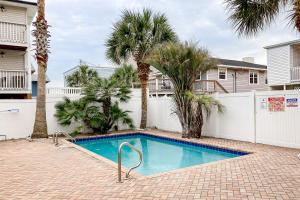 a swimming pool with palm trees and a white fence at Seahorse Serenity in Myrtle Beach
