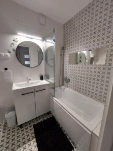 uma casa de banho com um lavatório, uma banheira e um espelho. em Odpocznij w Lesku em Lesko
