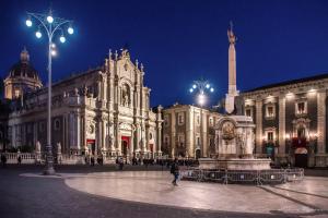 un grande edificio con una fontana di fronte ad esso di notte di MOUSUITE a Catania