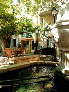 een fontein voor een huis met stoelen en een vijver bij Auberge de la Fontaine in Rians