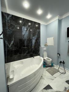 ein Badezimmer mit einer großen Badewanne und einem WC in der Unterkunft Рахат апарт in Aqtöbe