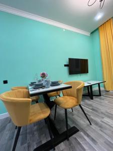 a dining room with a table and chairs and a tv at Рахат апарт in Aktobe
