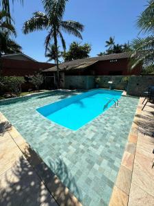 a large swimming pool in a yard with a palm tree at Casa com piscina em boraceia a 400 metros da praia in Boracéia