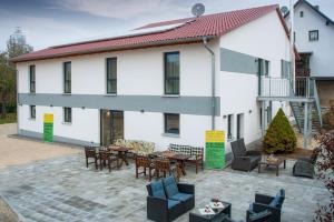 a large white building with a patio with tables and chairs at Privatpension zur Schwarzach in Greding