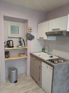 a small kitchen with white cabinets and a sink at Entre Montagnes et Lacs in La Bresse