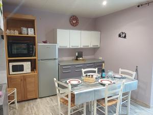 a kitchen with a table with chairs and a refrigerator at Entre Montagnes et Lacs in La Bresse