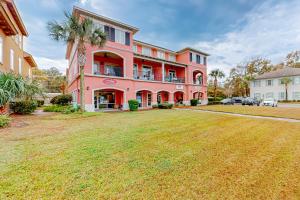 uma casa cor-de-rosa com um grande quintal em frente em Villa Christol em Bluffton