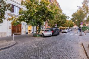 a cobblestone street with cars parked next to a tree at TRASTEVERE SUITE EXPERIENCE in Rome