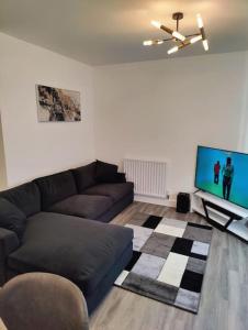 a living room with a couch and a flat screen tv at 2 bedroom en-suite apartment in Basildon, Essex (Enjoy the simple things in life) in Laindon
