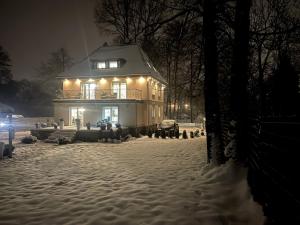 a house with lights on in the snow at night at Villa Śnieżka in Kowary