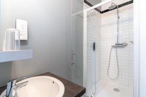 a white bathroom with a shower and a sink at CALM Appart' & Hostel in Lille