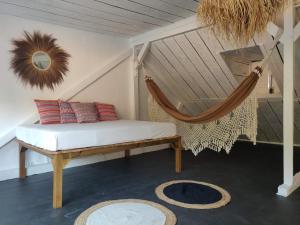eine Hängematte in einem Zimmer mit einem Bett und einem Teppich in der Unterkunft Maison Bernabet - Rooftop avec vue sur la Montagne Pelée in Saint-Pierre