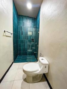a bathroom with a toilet and a blue tiled shower at Selva Pacific Mountain Beach retreat in Quebrada Ganado