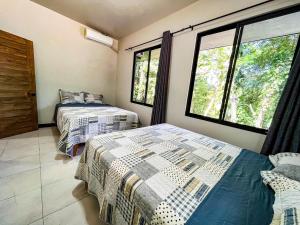 two beds in a room with two windows at Selva Pacific Mountain Beach retreat in Quebrada Ganado