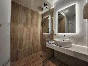 a bathroom with a sink and a shower with a mirror at B21Residence in Athens