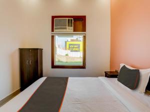a bedroom with a bed and a window with a air conditioner at North Hotel & Lawn in Lucknow
