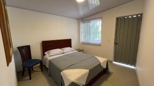 1 dormitorio con 1 cama, 1 silla y 1 ventana en Villa La Felisa Hospedaje Campestre Pandi Cundinamarca, en Pandi