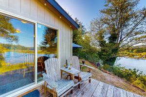 - deux chaises et une table sur la terrasse couverte d'une maison dans l'établissement Lakefront Lookouts 1 & 2, à Lakeside