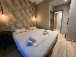 una camera da letto con un grande letto bianco con asciugamani di B21Residence ad Atene