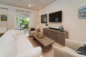 a living room with white furniture and a flat screen tv at Royal Westmoreland - Sugar Cane Ridge 3 townhouse in Saint James