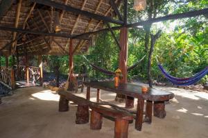 a picnic table and benches in a pavilion with hammocks at Magia Verde Lodge in Puerto Misahuallí