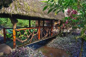 drewniany most z dachem krytym strzechą w obiekcie Magia Verde Lodge w mieście Puerto Misahuallí