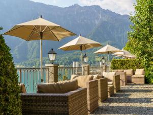 uma fila de cadeiras e guarda-sóis num pátio em Hotel Seeburg - Adults only em Ringgenberg