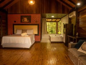 une chambre avec un lit et un mur de briques dans l'établissement Chalé Canadense com Hidromassagem Pousada Índios Koroados, à Praia Grande