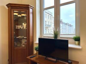 a tv sitting on a table in front of a window at Apartament z widokiem na stary rynek in Wejherowo