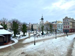 a snow covered street in a city with buildings at Apartament z widokiem na stary rynek in Wejherowo