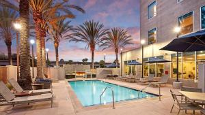 a swimming pool with palm trees and a building at AC Hotel by Marriott Los Angeles South Bay in Los Angeles