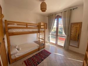 Tamraght OuzdarにあるMAKTUB SURF HOUSEの二段ベッド2台と窓が備わる客室です。