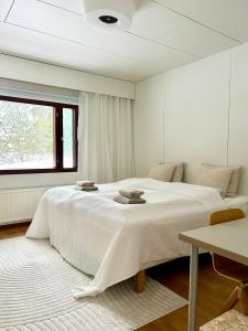 a white bedroom with a large bed with a window at Idyllinen asunto lentokentän lähellä in Vantaa