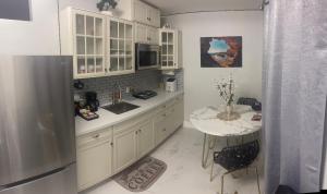 cocina con armarios blancos, mesa y nevera en Fantastic Suite en Las Vegas