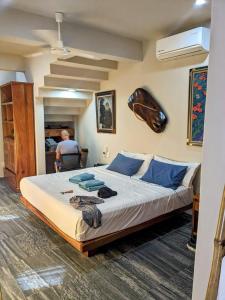 a bedroom with a large bed and a man sitting in a chair at Suites La Hacienda in Puerto Escondido