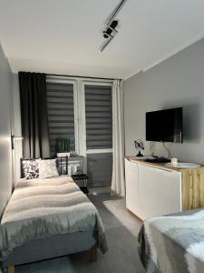 a bedroom with a bed and a flat screen tv at Apartament Na Wspólnej in Sosnowiec