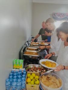 um grupo de pessoas preparando comida em um buffet em Al khitaym guest house em Sa‘ab Banī Khamīs