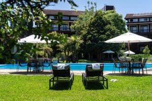 um grupo de cadeiras e guarda-sóis ao lado de uma piscina em Hotel Alpestre em Gramado