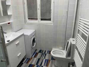 uma casa de banho com uma máquina de lavar roupa e um WC em appartement Corentin Cariou em Paris