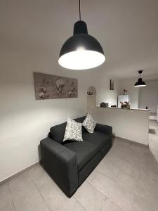 a black couch sitting in a living room under a light fixture at La casa di Stella in Isernia