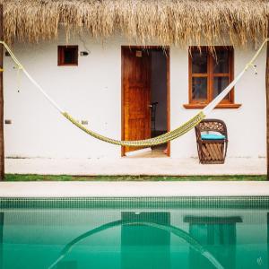 a house with a hammock in front of a swimming pool at Kinta Kan Hotel Boutique Cozumel in Cozumel