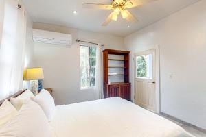 Schlafzimmer mit einem weißen Bett und einem Deckenventilator in der Unterkunft Casa Tranquila in Caye Caulker