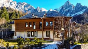 a wooden house with mountains in the background at Hotel Paladin in San Martino di Castrozza