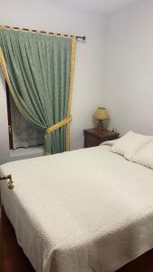 トラマカスティリャ・デ・テナにあるApartamento La Pinadaのベッドルーム1室(緑のカーテン付きのベッド1台付)