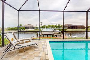 a swimming pool with two chairs and a boat in the water at Palm & Friends Estate in Cape Coral