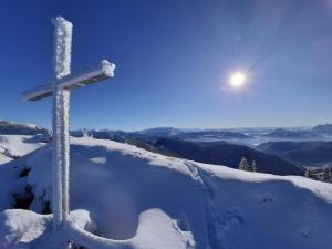 una cruz sobre una montaña cubierta de nieve en Ferienwohnung Bergliebe en Staudach-Egerndach